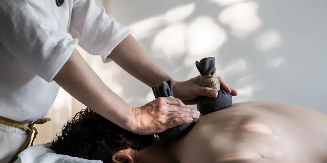 man wordt gemasseerd met kruidenstempels